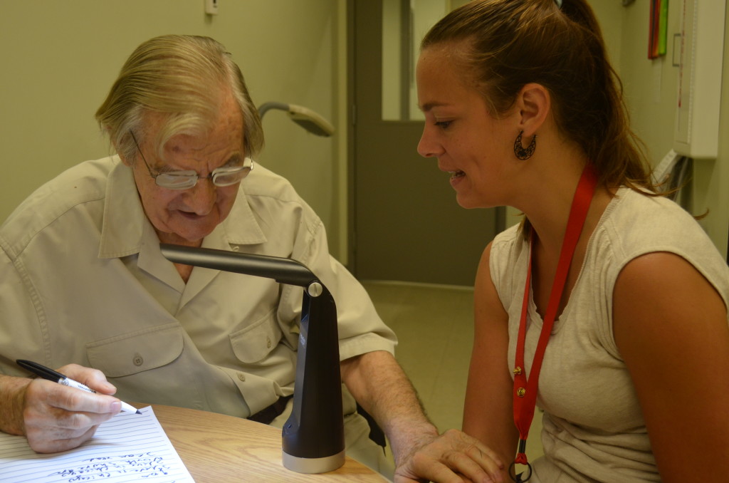 Occupational therapist, Laura Hayes demonstrates wide lined paper and task lighting to assist a low vision patient write a grocery list