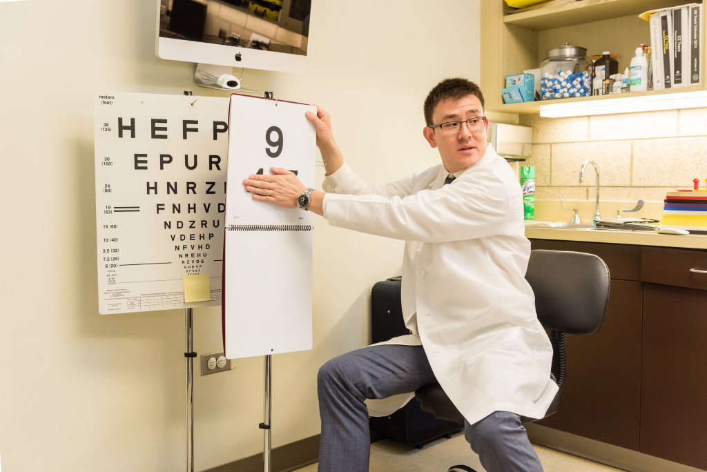 A resident of Optometry flips pages of an eye chart