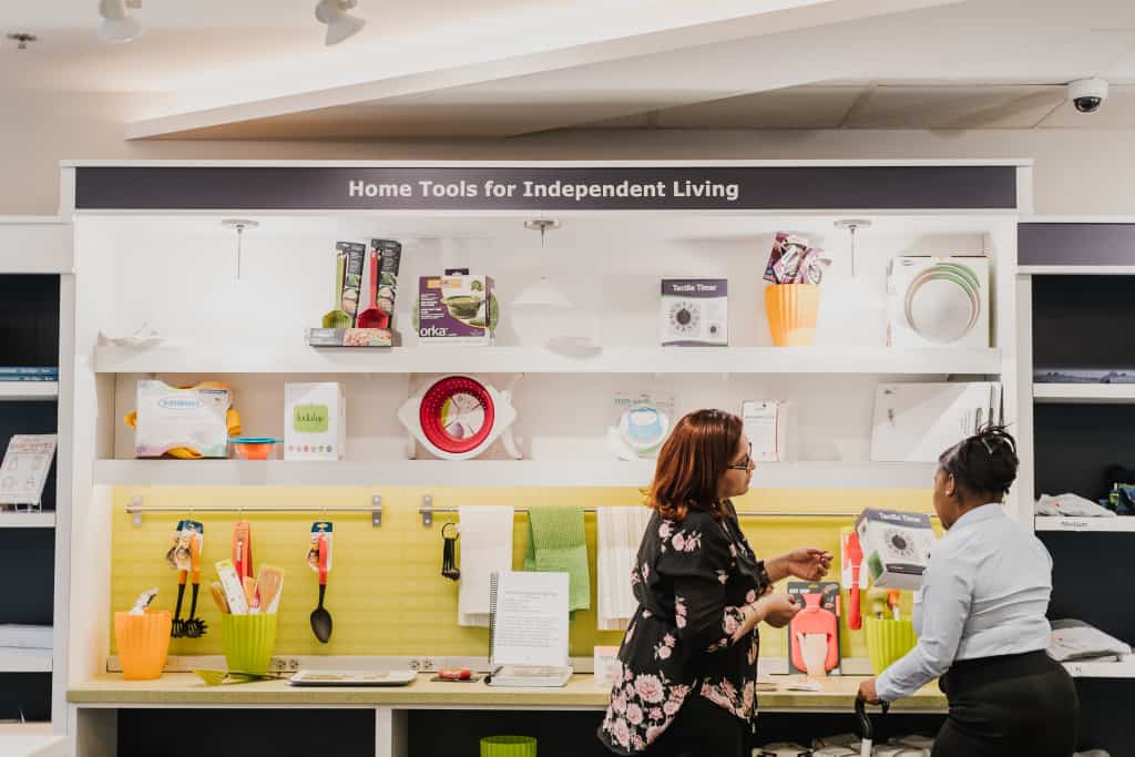 Photograph of two individuals looking at kitchen items at the Tools for Living Store. 