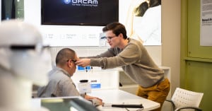 An assistive technology specialist places a pair of OrCam MyEye 2 glasses on a client who is blind during a product demonstration