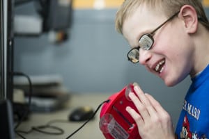 A child with visual impairment uses a device to help him on his computer