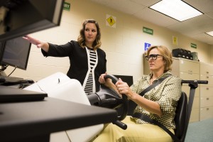 A patient is instructed by a low vision specialist on a driving simulator