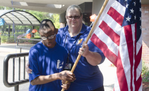 A special needs child carries the US flag along with his teacher to kick off the special games at The Chicago Lighthouse