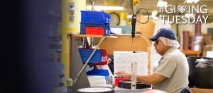 A man who is blind is assembling a clock at his workstation