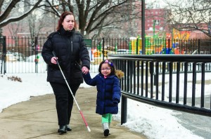 Mother with a white cane and daughter walking together.