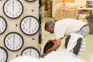 Worker at Chicago Lighthouse Industries packaging clocks.