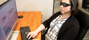 A woman who is blind works in a customer care center answering calls.