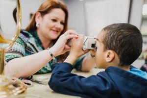 A female technician holds a viewer to a child's face to test his vision