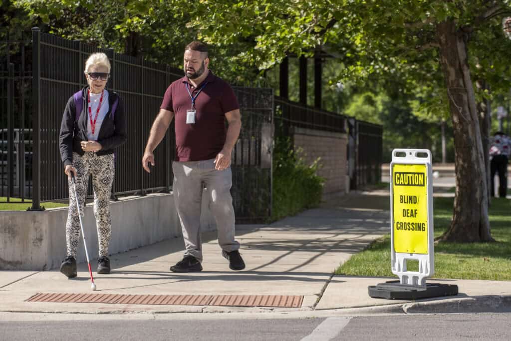 A woman receives orientation and mobility training from an O & M specialist while approaching an intersection near The Chicago Lighthouse