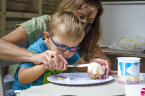 A three year old boy who is visually impaired frosts a cupcake with his vision teacher.
