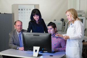 A group of 3 researchers evaluate a patient who is visually impaire as he tests out a new software program