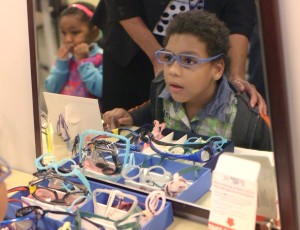 A young boy sees himself in the mirror with new glasses