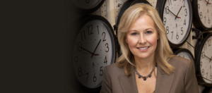 Dr. Janet Szlyk in front of a wall of clocks in the clock factory