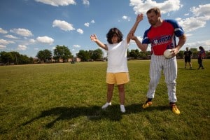 A coach teaching a participant to play beep baseball