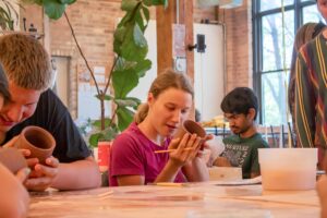A group of youth from the Summer in The City program work on pottery pieces.
