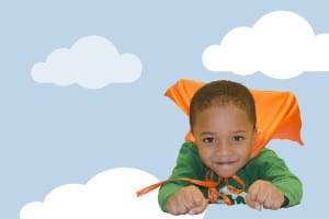 Boy appearing to be flying in sky, wearing a cape