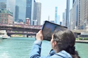Photography for all student takes a photo while on a boat