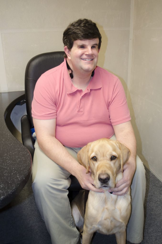 Chicago Lighthouse employee Brett Shishkoff smiles with his dog guide Poet. 