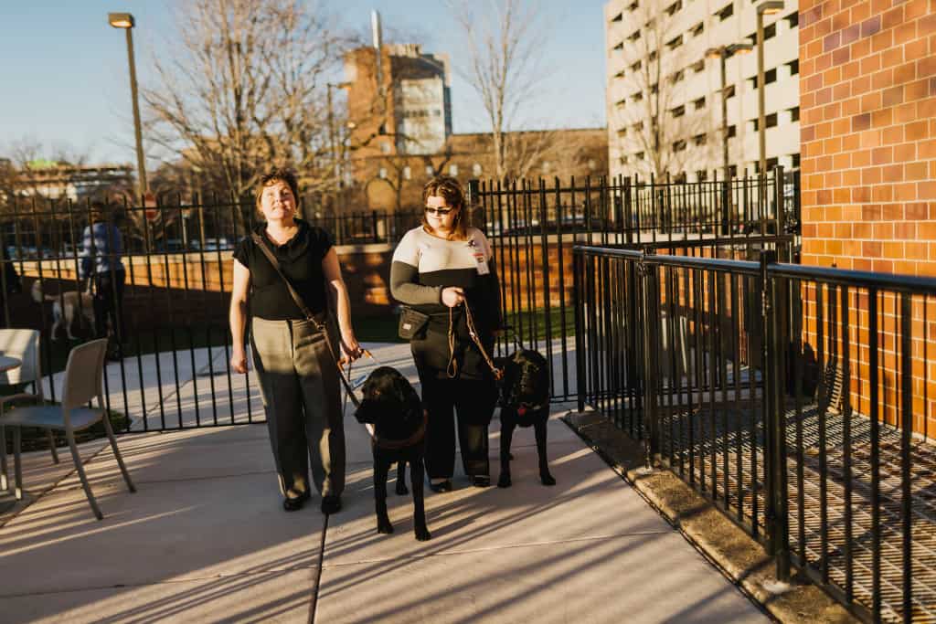 Chicago Lighthouse employees Maureen Reid (left) and Adnana Saric (right) walk outside with their dog guides. 