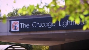 A tree branch in the foreground frames the sign for The Chicago Lighthouse