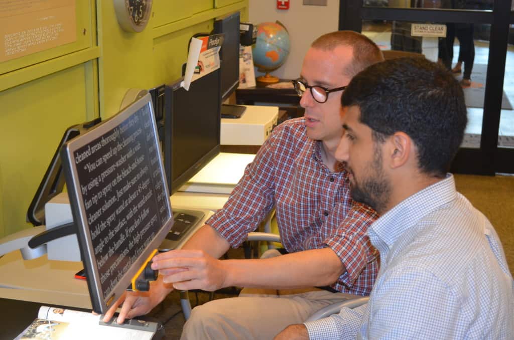 A client receives guidance on how to use a magnifying screen for reading.