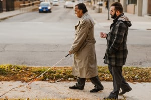 Orientation and Mobility Instructor Jaret Bozigian works with a client as they use their white cane while walking on the sidewalk