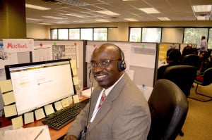 Michael Smith, an employee of our Illinois Joining Forces Call Center, smiles at his desk.