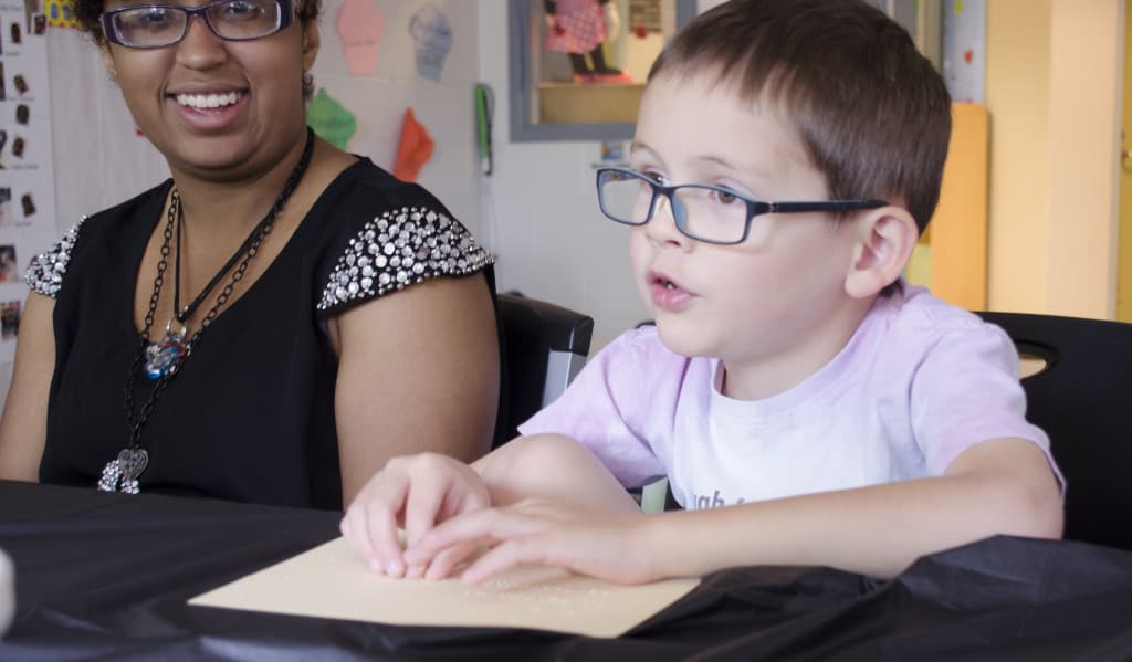A preschool age boy reads Braille