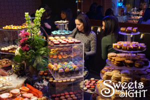 Guests at Sweets for Sight select desserts from a table filled with colorful cupcakes, cookies and other treats