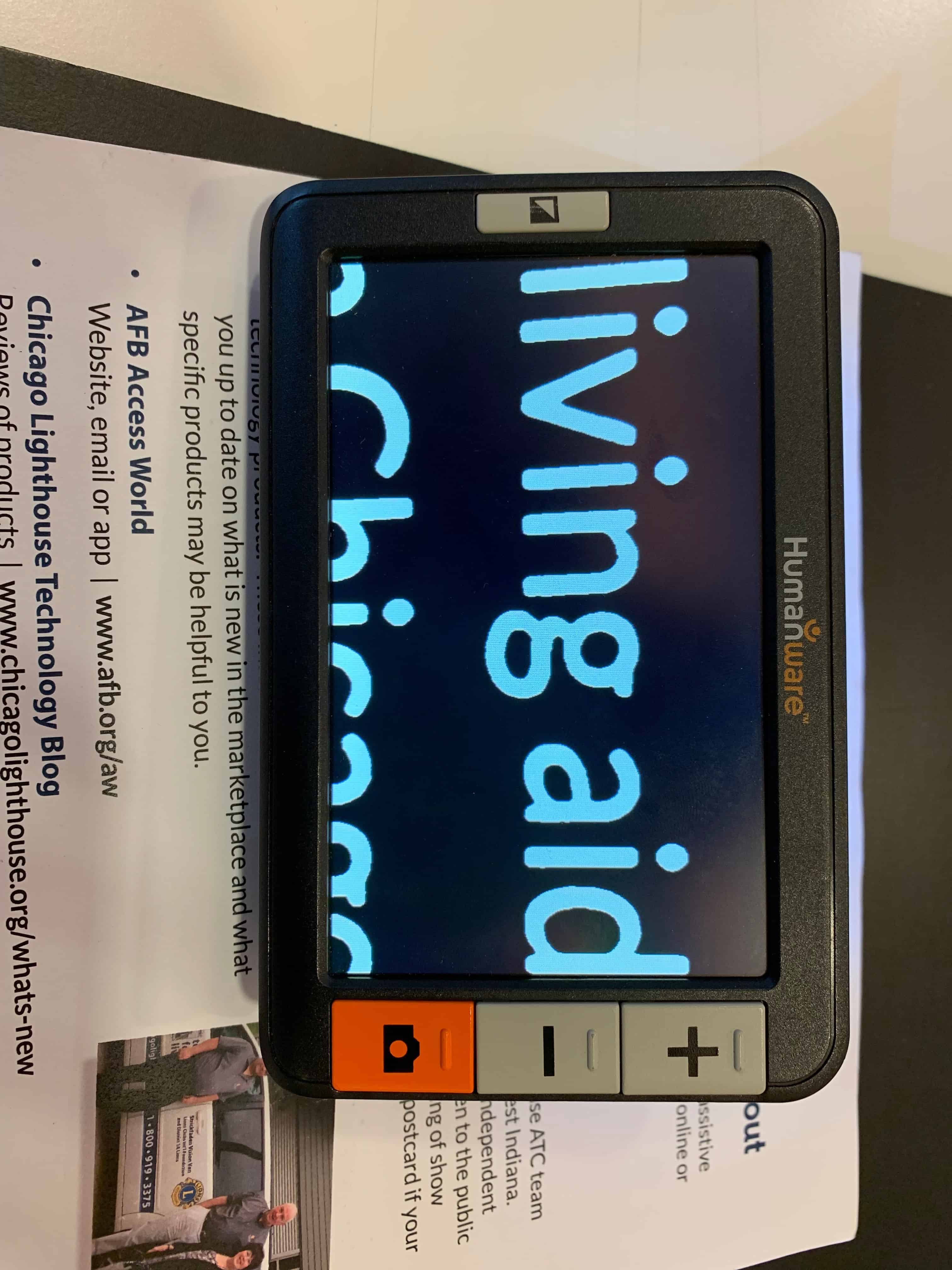 The Humanware Explore 5 device is shown magnifying text on a piece of paper.
