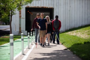 A group of teens who are visually impaired or blind along with their counselors walk on the sidewalks of downtown Chicago