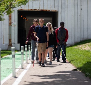 A group of teens who are visually impaired or blind along with their counselors walk on the sidewalks of downtown Chicago