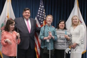Hannah, Governor Pritzker, Daniel, Sandy Murillo and Chicago Lighthouse President/CEO Janet Szlyk pose in front of the US and Illinois State flags