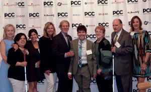 Dr. Janet Szlyk, Sandy Murillo, Jessica Grant, Angela D'Antonia, Gary Rich, Dominic Calabrese, Barb Kesteloot, Jim Kesteloot and Lisa Birmingham pose by the Publicity Club of Chicago's banner