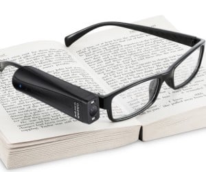OrCam MyEye2 device attached to a pair of glasses resting on top of a book