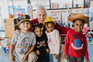 Larry Broutman poses with 4 children from The Judy and Ray McCaskey Preschool