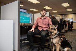 A customer care representative who is blind is picutred with his guide dog in the UI Health call center