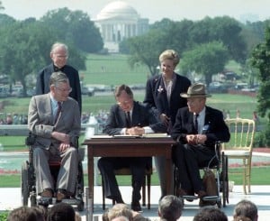 President George H.W. Bush signs the Americans with Disabilities Act during a ceremony on the South Lawn of the White House on July 26, 1990
