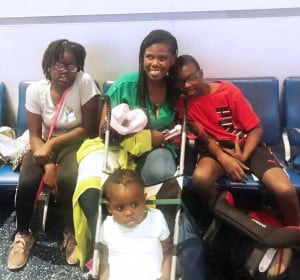 Image of Kalari sitting and smiling with her three children
