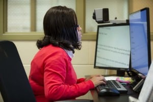 woman reading a computer screen using a magnifying device