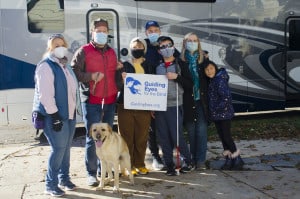 Flyer the dog surrounded by his new family, Dr. Janet Szlyk of the Lighthouse, and an employee from guiding eyes for the blind