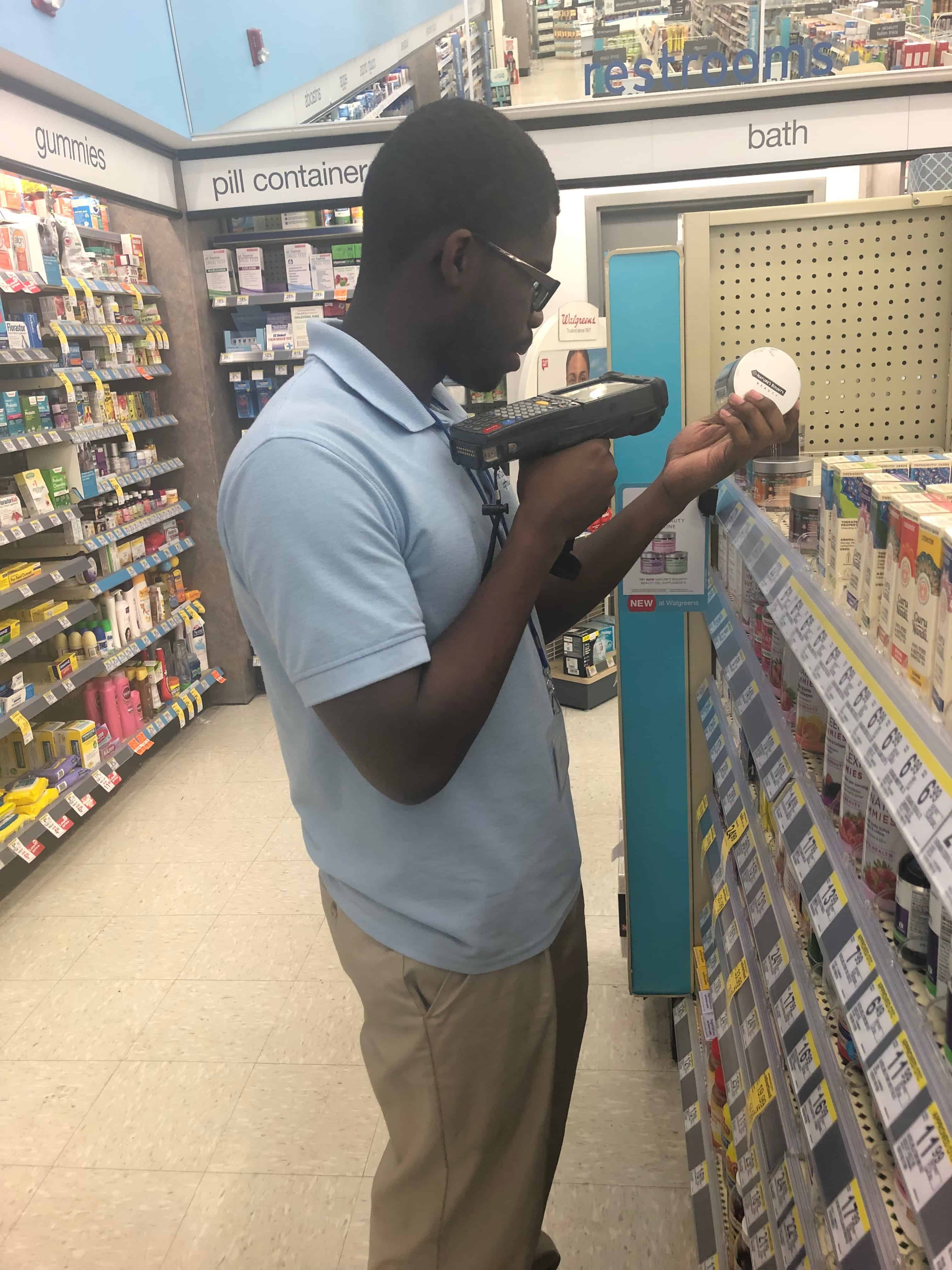 Teen in The Lighthouses' First Jobs program working in a walgreens, scanning products on the shelf
