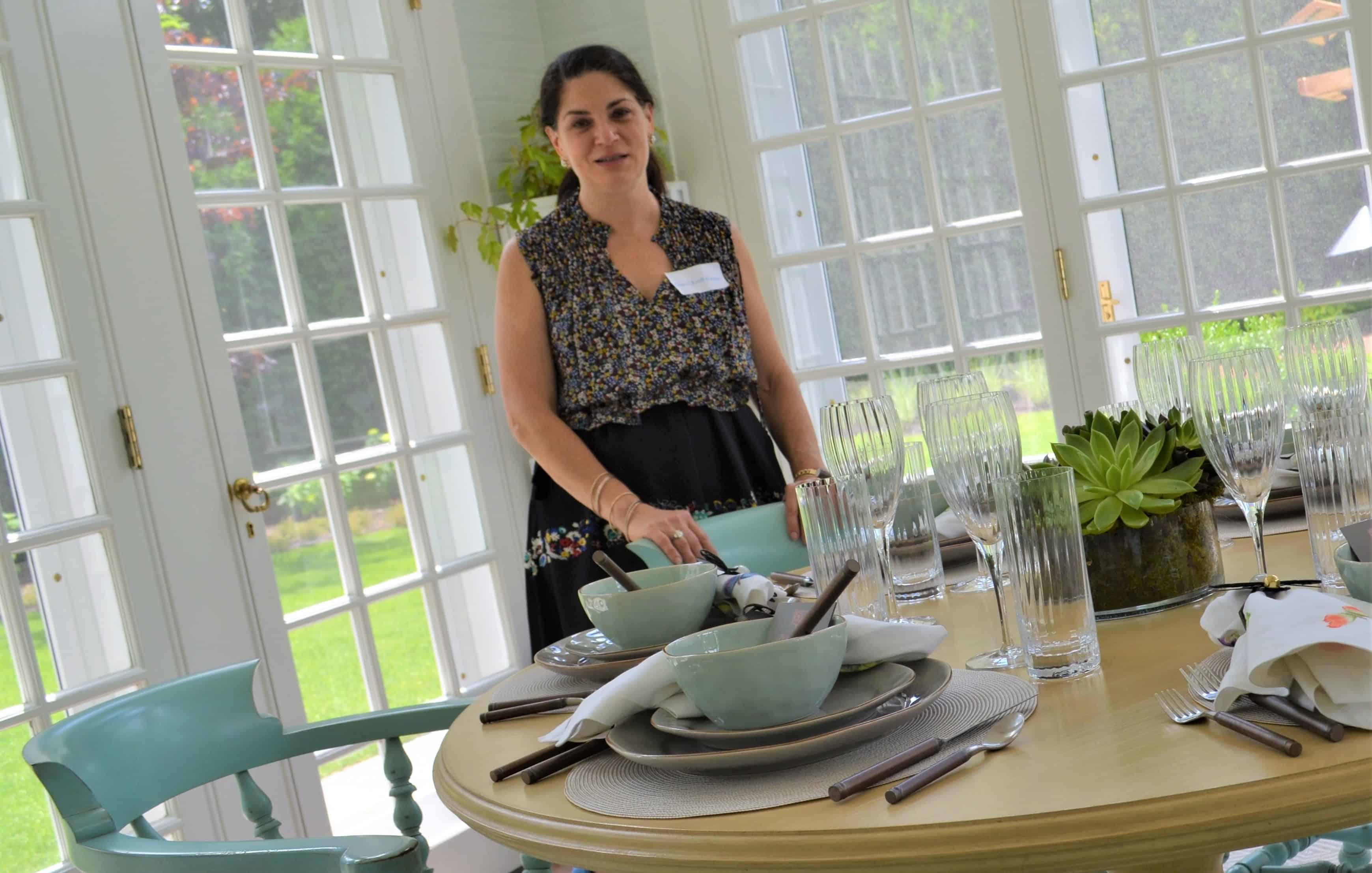 Ceryl Kraff-Cooper smiling and standing behind a table at the chicago lighthouse's house and garden walk