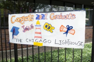 A tactile paper banner is displayed across the fencing of The Lighthouse. Sign reads: Congrats 2021 Graduate Jesus, The Chicago Lighthouse