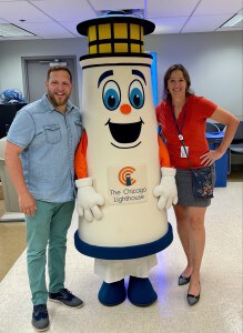 An eight-foot tall lighthouse mascot (with Intern Emily inside) is flanked by her supervisors, Phil and Lisa