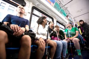 A group of young adults who are blind or visually impaired ride an el train in Chicago