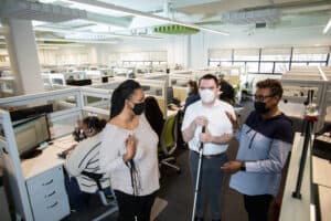 Supervisors (2 of which are blind) have a meeting in a call center where many agents are taking calls