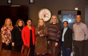 Group photo of 7 people from The Lighthouse leadership team as well as representative from IDHS presenting Dr. Janet Szlyk with the Employer of the Year award