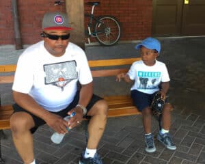 Glenn and his son sitting on a bench in baseball attire
