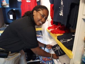 A woman folds shirts in a gift shop